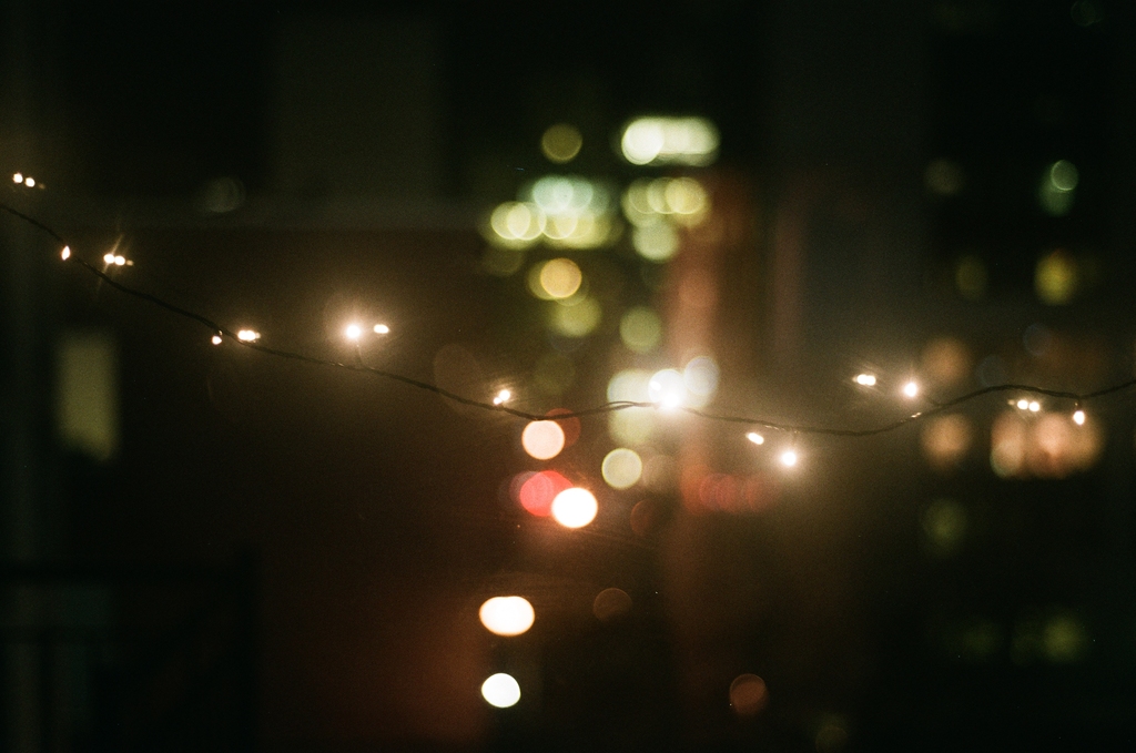 fairy lights strung across the frame, with city lights in heavy bokeh in the background