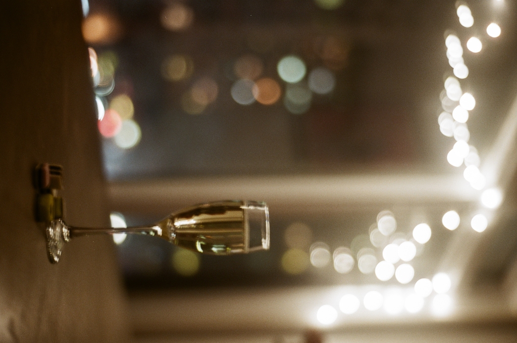 a champagne flute on a table, under fairy lights, with allsorts candies