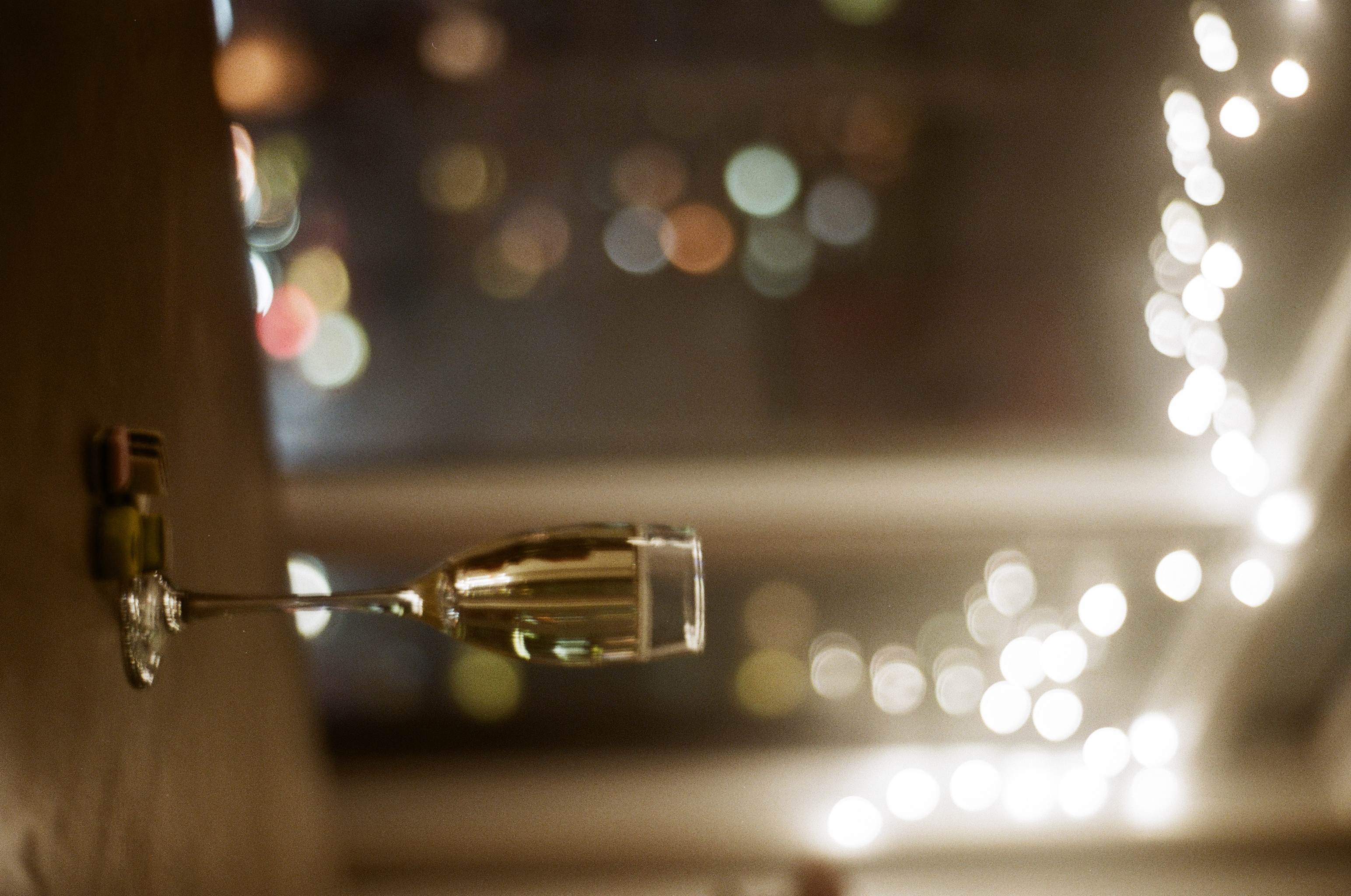 a champagne flute on a table, under fairy lights, with allsorts candies