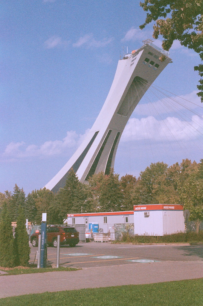 The tower of the Olympic Stadium rising up over a parking lot with several trailers