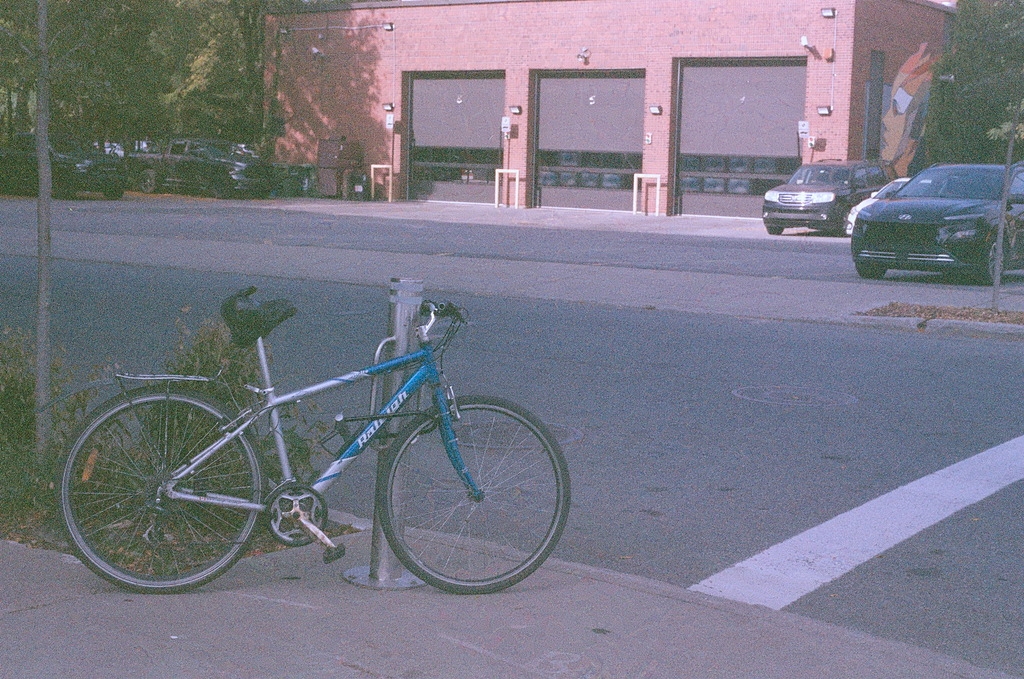 A bicycle chained to a post on the sidewalk