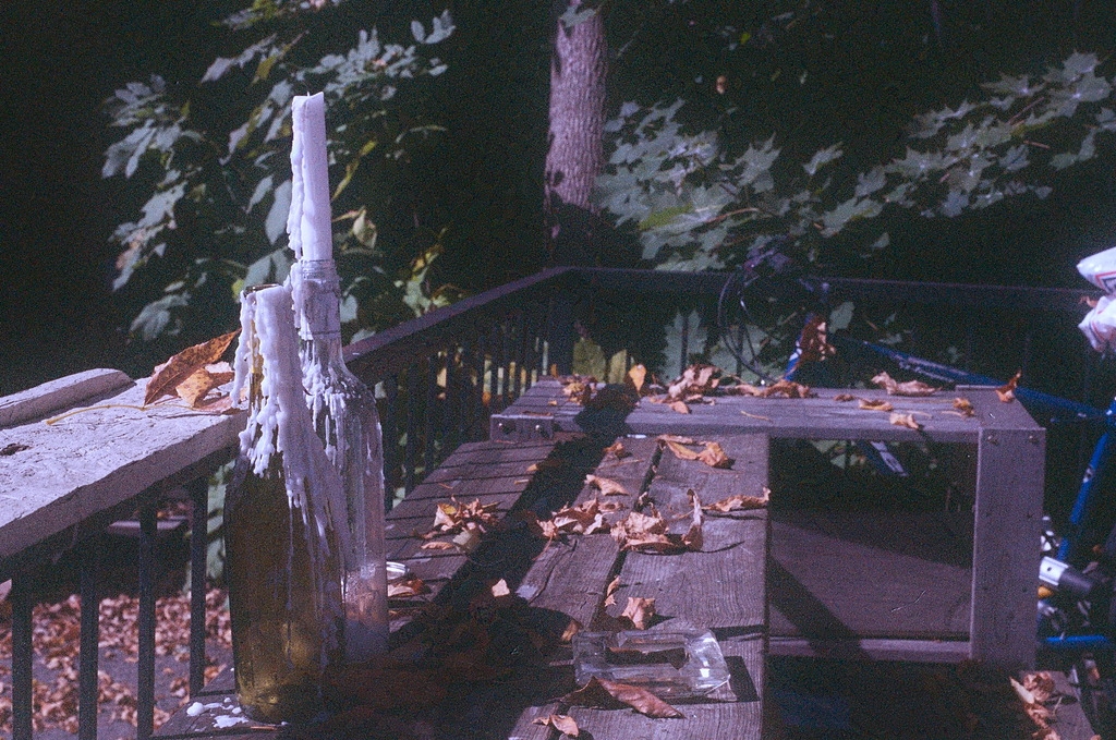 Candles stuck in wax-covered bottles on a picnic table