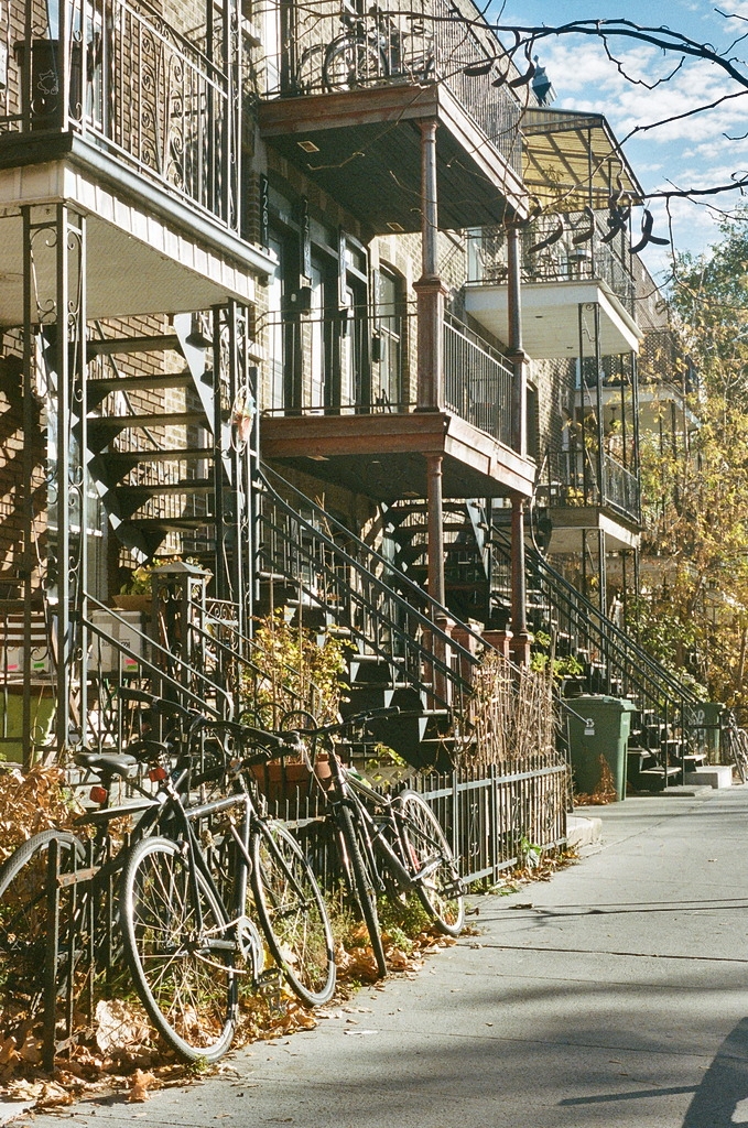 Bikes chained on the sidewalk under typical Montréal stairways