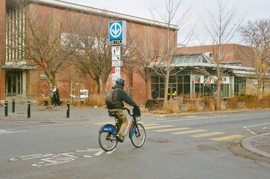 A person on a Bixi bike crosses the intersection in front of Laurier metro station