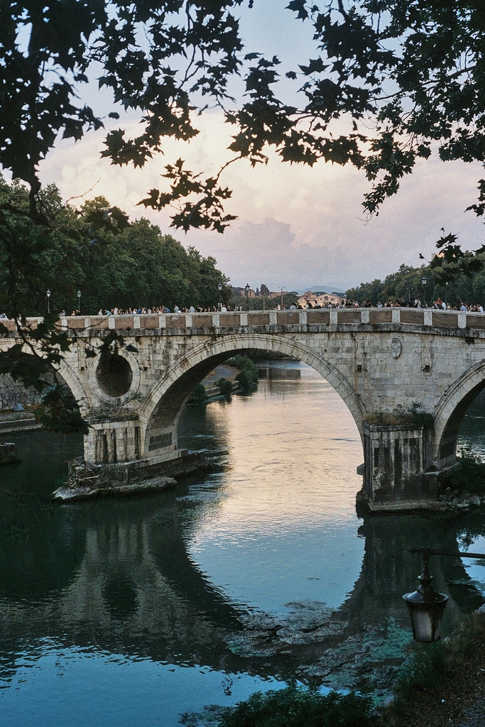 The Ponte Sisto bridge in the evening, with many pedestrians, and clouds towering in the background