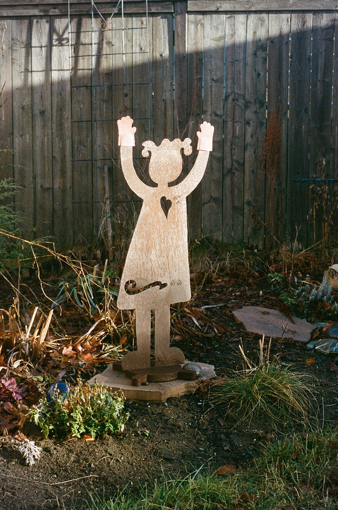 A flat, rusted garden figure of a person with their arms raised