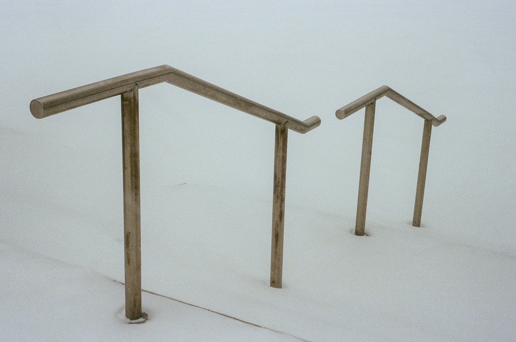 A set of handrails leading down to a snowy surface