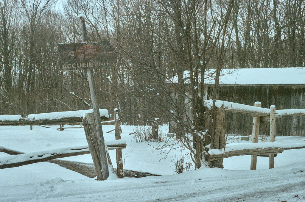 A welcoming sign on a wooden fence, in the snow