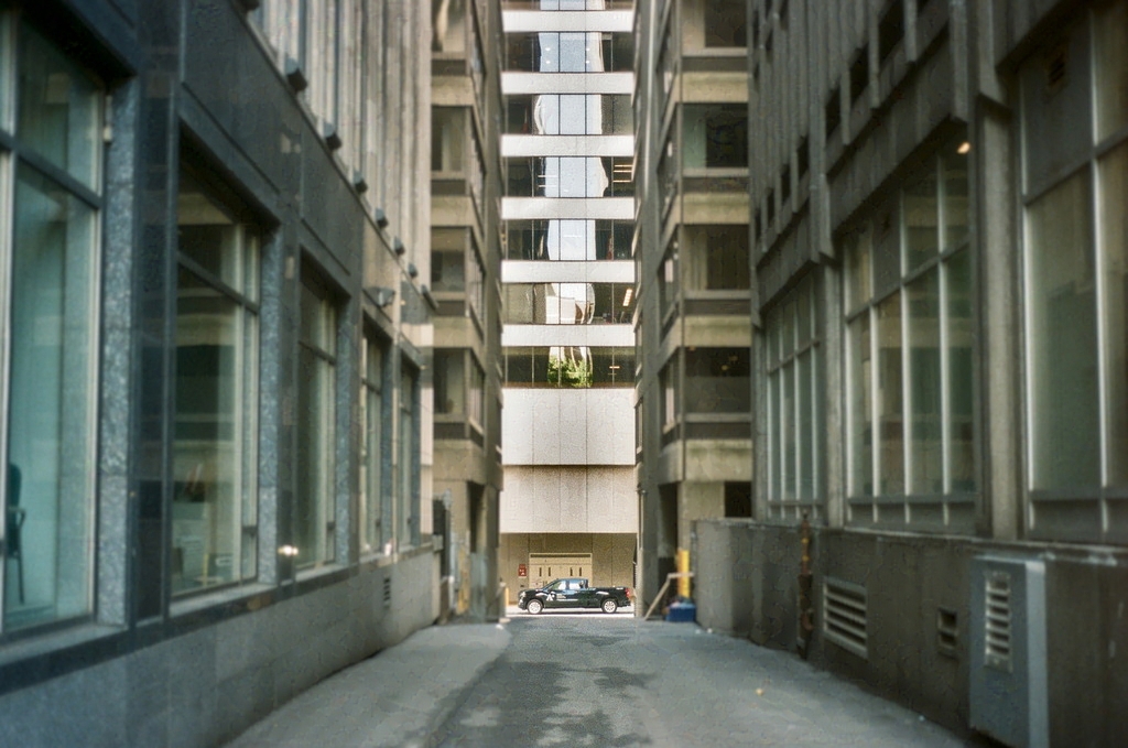 A jeep framed by tall buildings at the far end of an alleyway