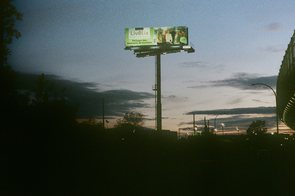 A lit billboard against a dusken sky, advertising a senior's residence