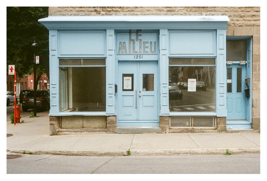The robin-egg blue storefront of Le Milieu, with À Louer signs in the windows