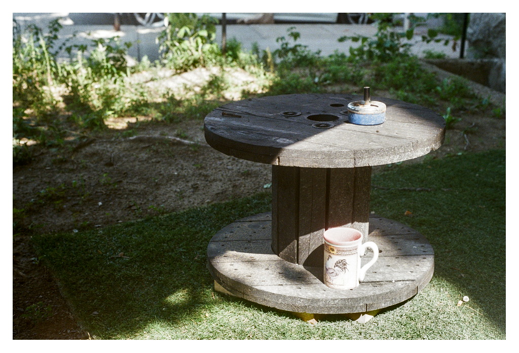 An overturned industrial wooden wheel serving as a table, with a coffee mug