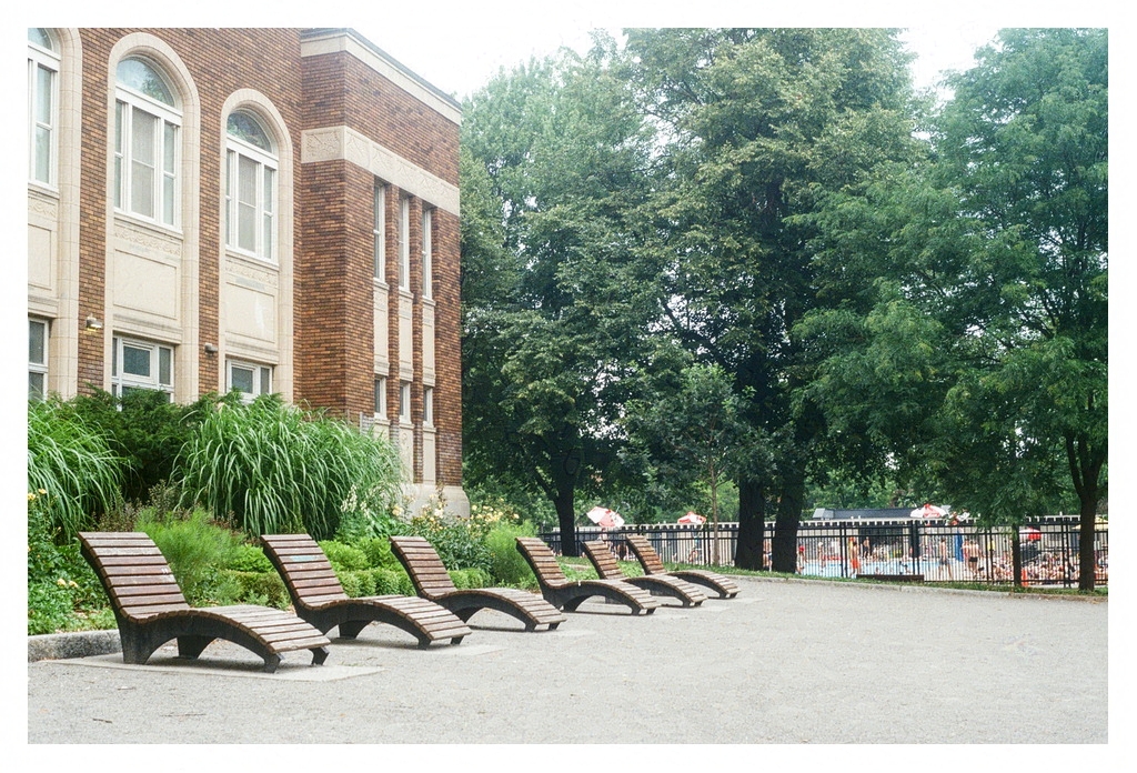 Sun tanning benches in the park, with a pool in the background