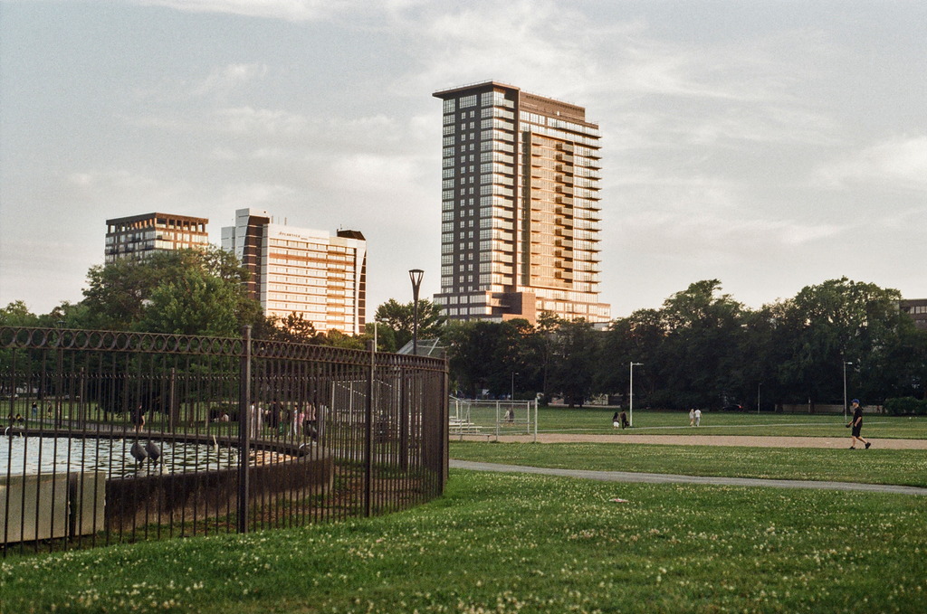 Condo buildings rise over the green sward of The Commons at sunset