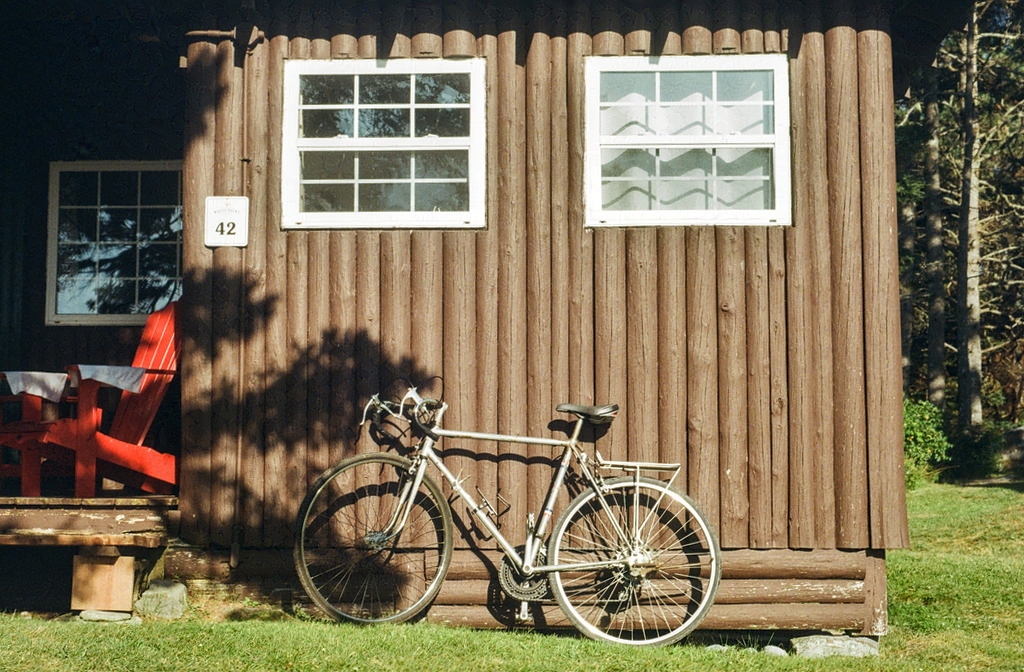 A bicycle leaning against a small cabin exterior
