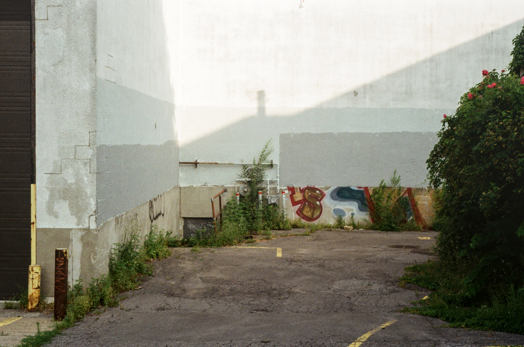 Slanted shadow of a roof across a sun-worn white wall