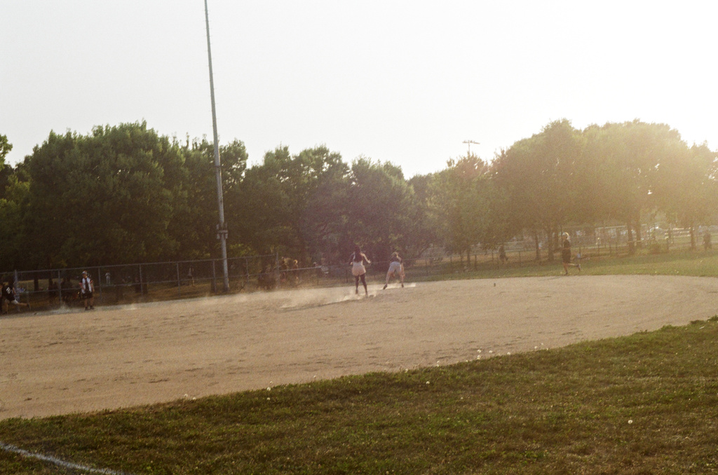 Dust flies at a pickup game of baseball at Parc Laurier at sunset