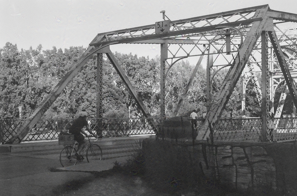 A cyclist approaches a steel swing bridge