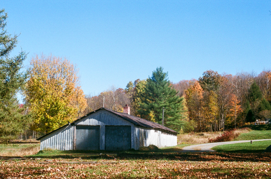 A low, broad cabin or garage on a mountain covered in autumn foliage