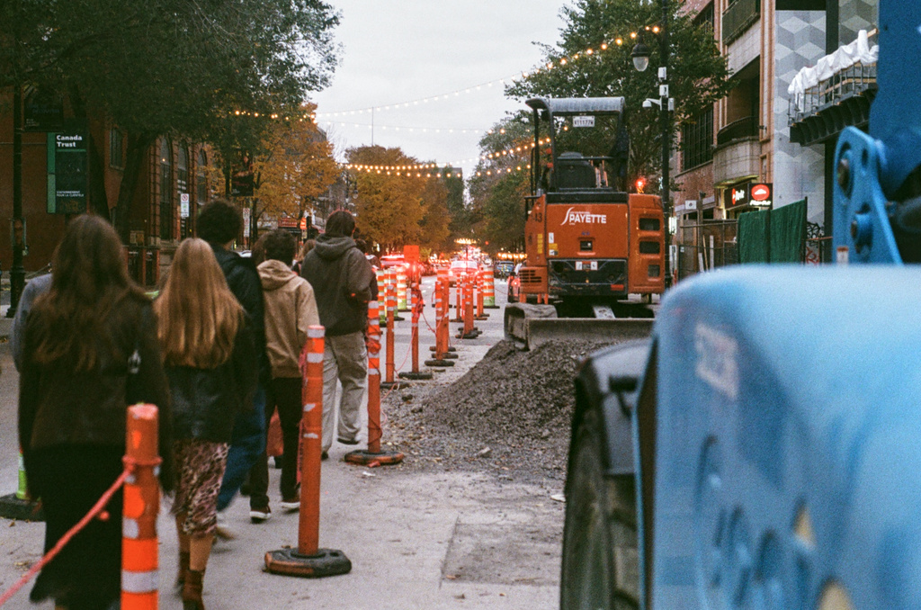 People walking along a cone-marked path around construction on St.-Laurent