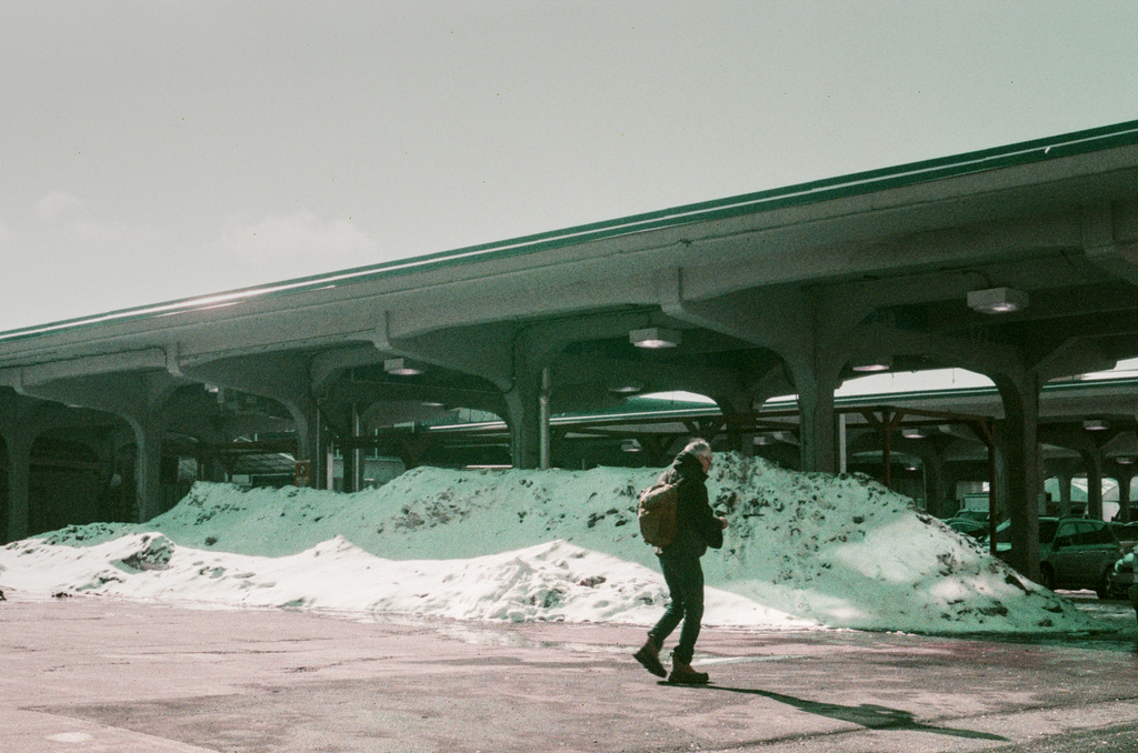 A man walks in front of mounds of snow in the empty outdoor bays of Jean-Talon Market