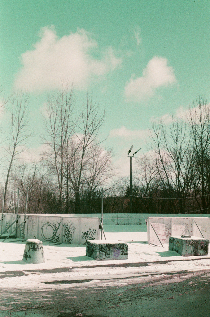 A few graffitied concrete bollards in front of an outdoor skating rink