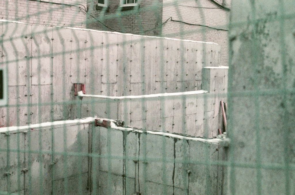 Concrete foundations for a building, viewed from behind a wire fence