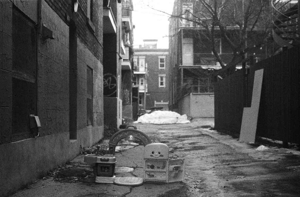 Small toy fridge with a smiley face, abandoned in an alleyway