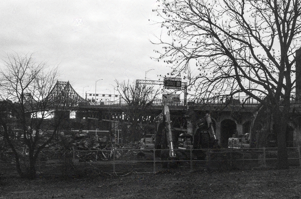 Idle excavators on the site of a demolished building up for construction, with the Jacques-Cartier Bridge in the background