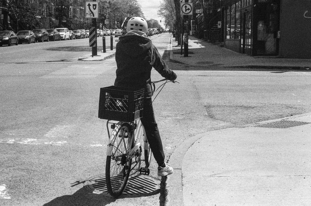 A cyclist rests their foot on the curb at a stop light