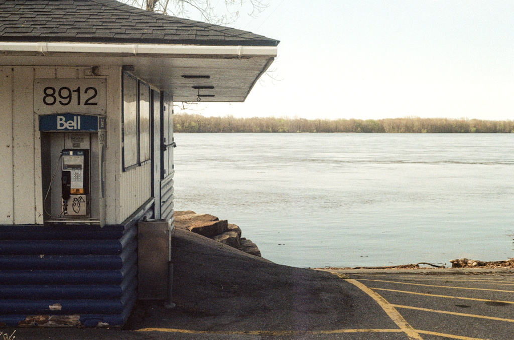 A phone booth on a shed by a boat ramp into a river
