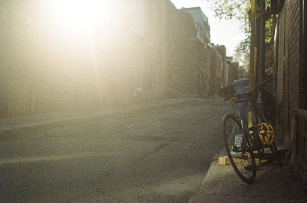 A bike parked on the sidewalk, under intense lens flare
