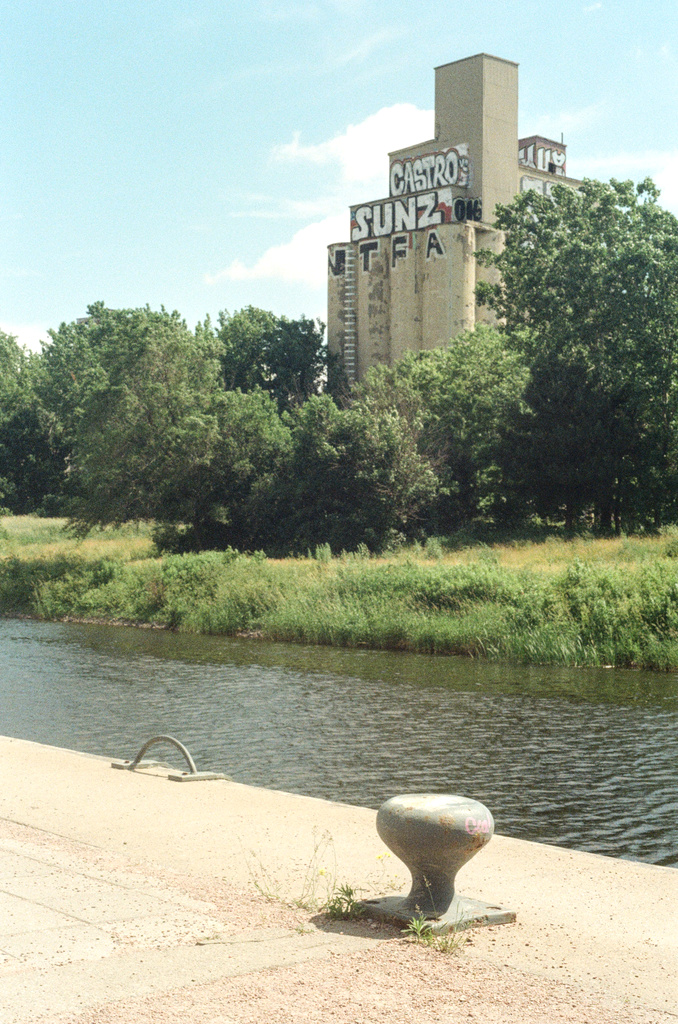 A silo building, a canal, and a mooring post