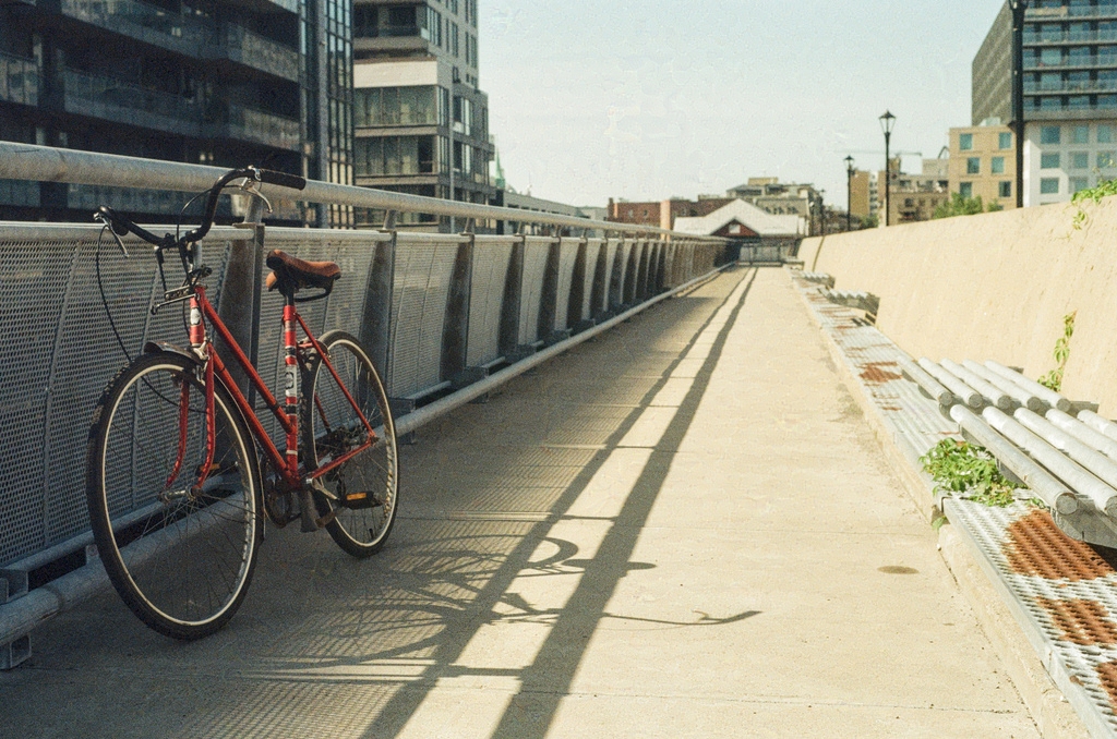 A red bike leaning against a metal fence