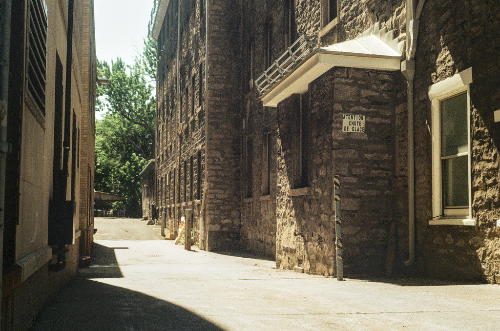 An alleyway between two stone buildings, in harsh light