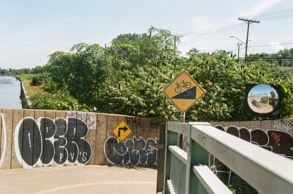 A hairpin turn in a bike path, with signage and a mirror