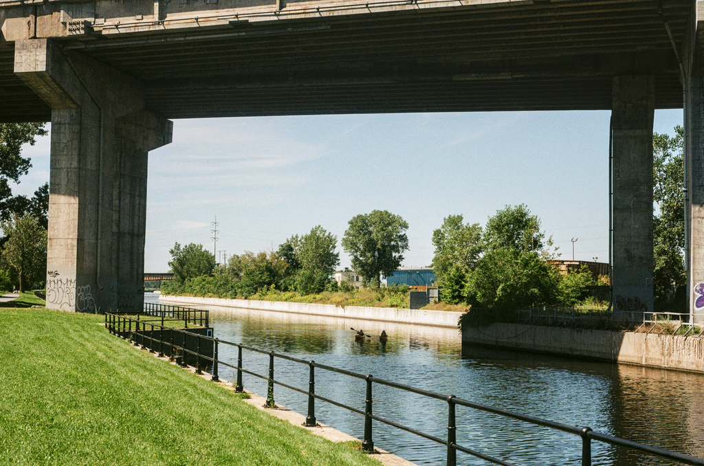 Two kayakers on a canal under a highway
