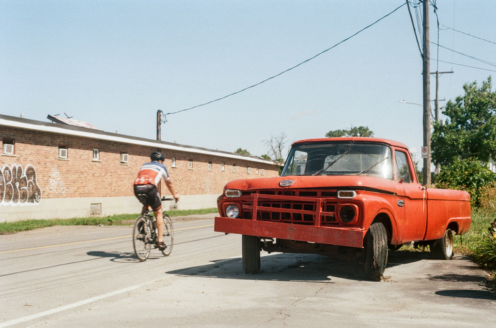 A cyclist passes a derelict red pickup truck