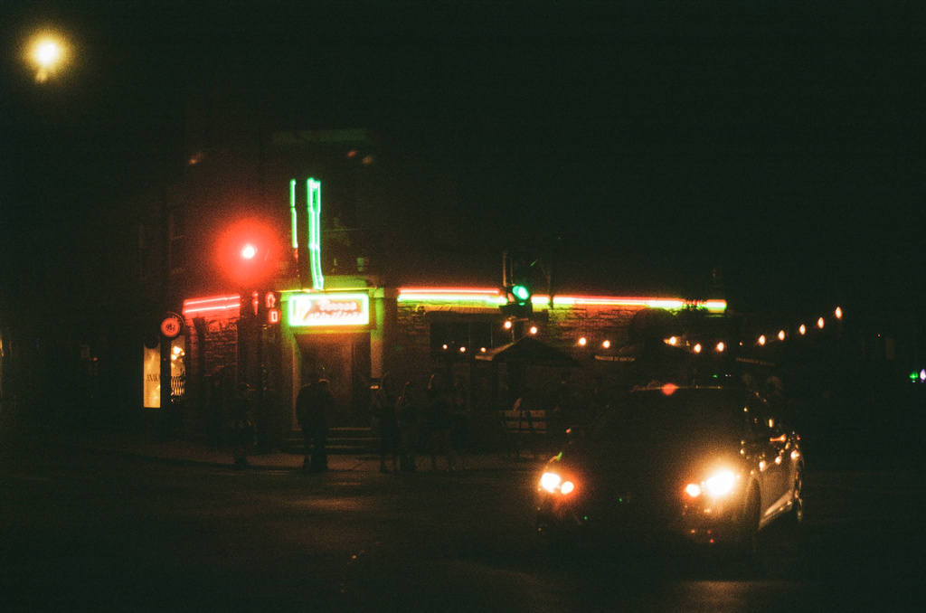 Cars, lights, & neon outside a bar at night