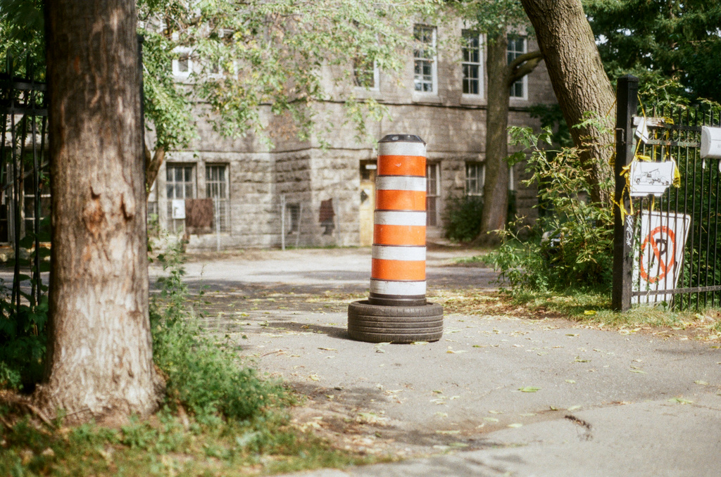 An orange-and-white construction pylon blocking entrance to a grey stone building