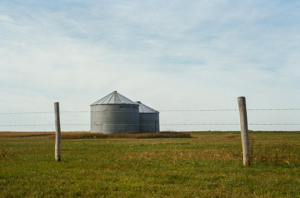 Two short silos behind a fence