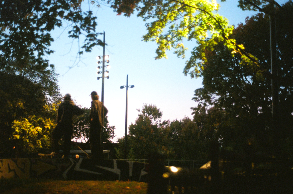 Two skaters wait at the top of an incline at night