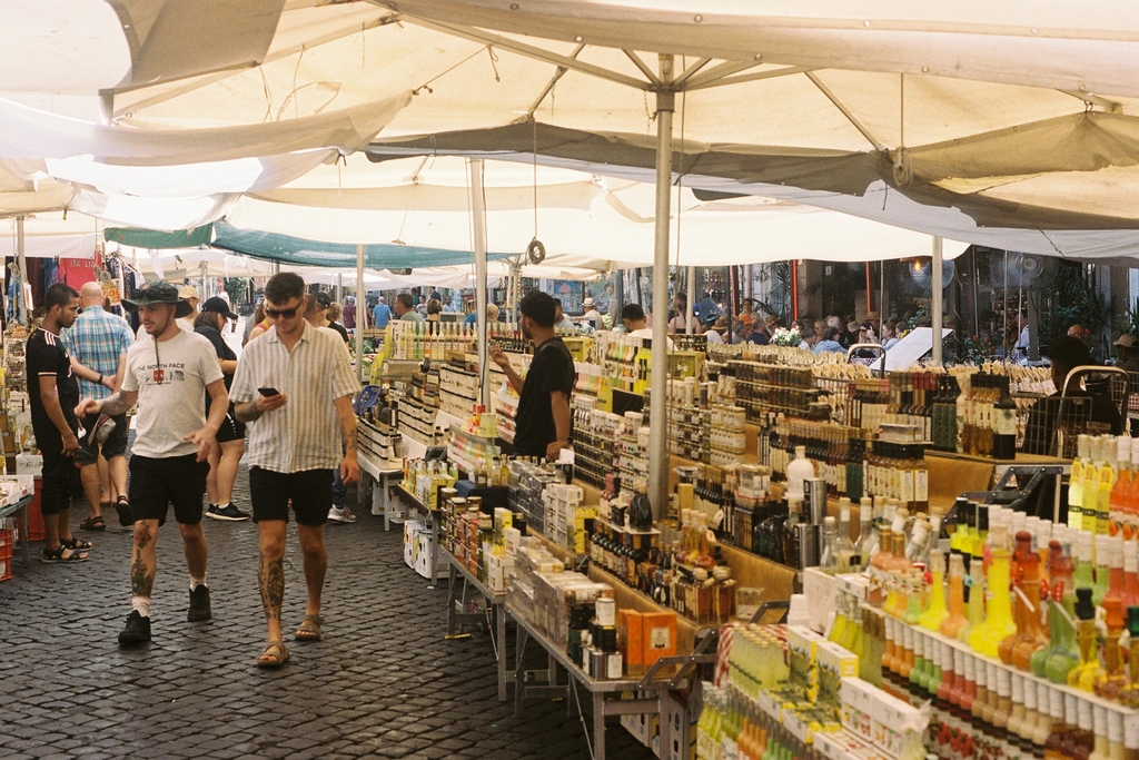 Merchants selling groceries & trinkets under wide parasols