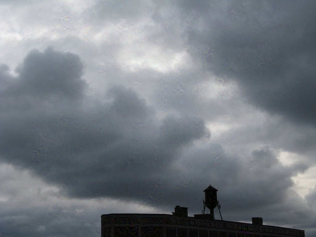 Silhouette of a water tower against a cloudy sky