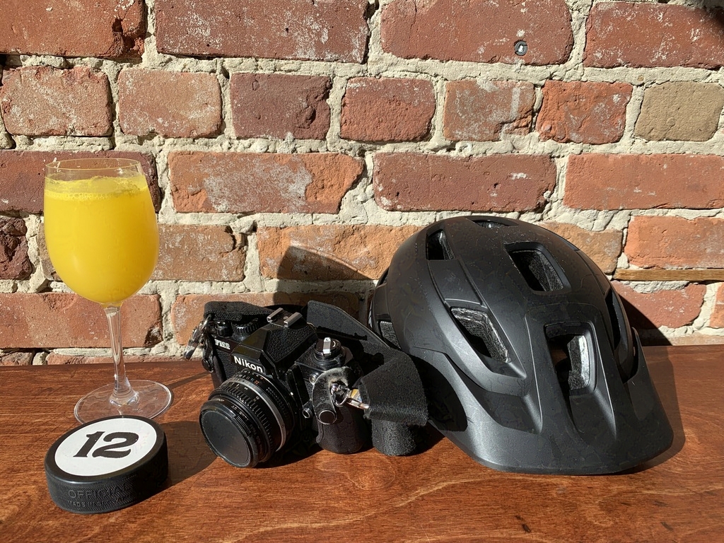 A mimosa, a hockey puck, and a bike helmet against a brick wall