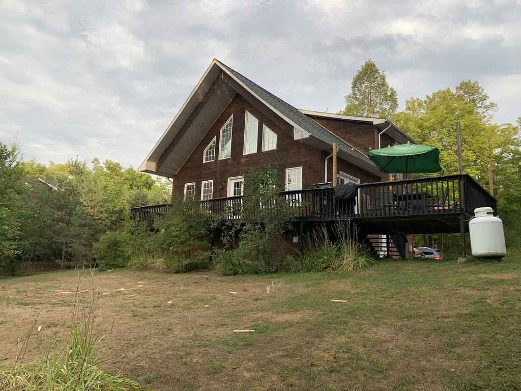 A cabin with a tall, triangular roof at the top of a little grassy rise