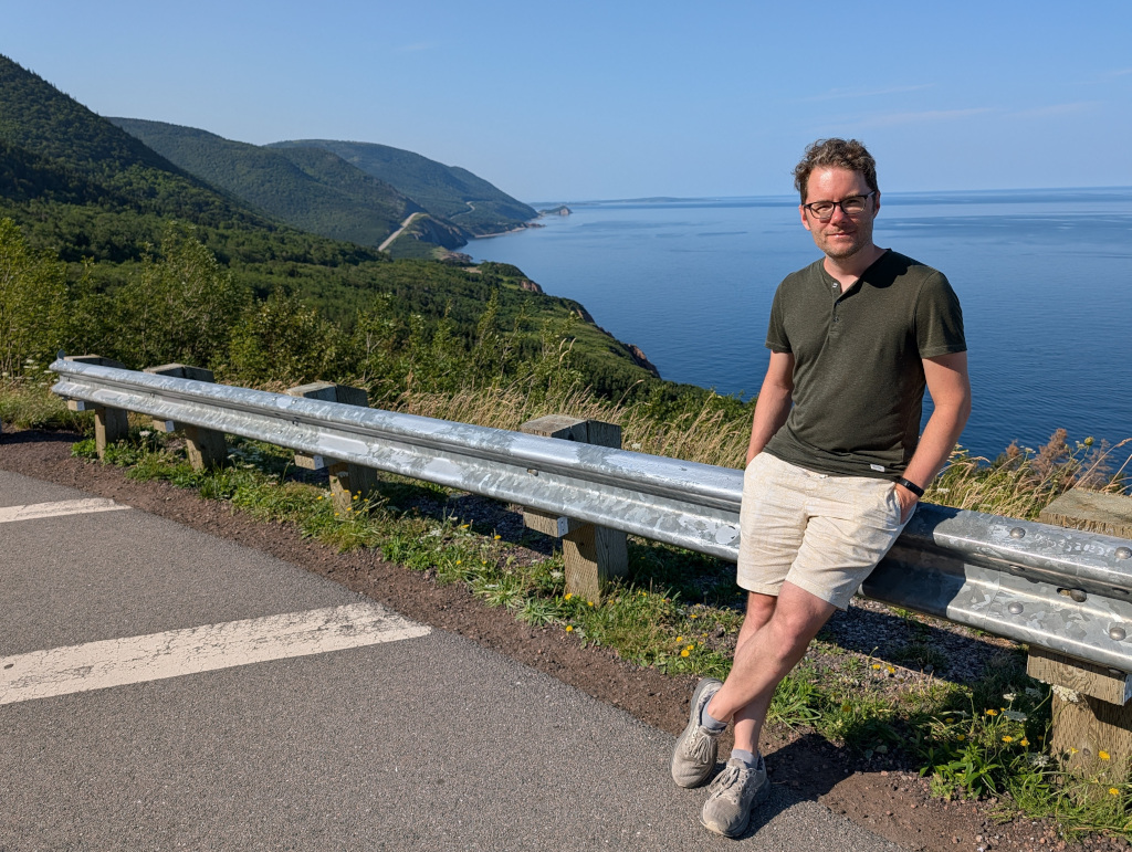 Me leaning against a railing, with the Cabot Trail extending to the horizon